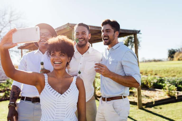 group of friends taking a selfie at an outdoor summer wedding