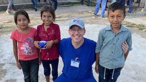 dr mark richardson standing with children in honduras