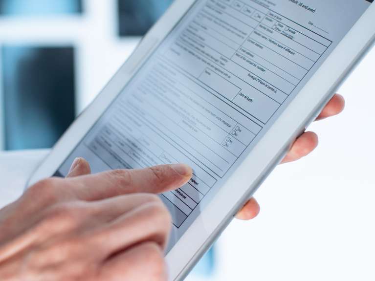 hand holding tablet with digital dental records on it